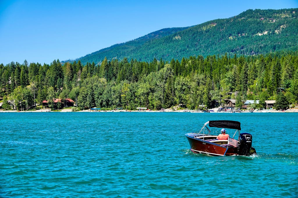 Enjoy leisure boating on serene Whitefish Lake with lush mountain views.